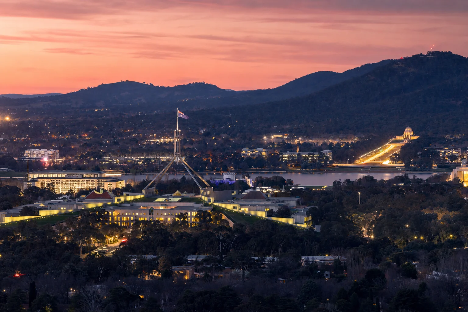 Canberra at dusk, the city lights and the lake below the hills