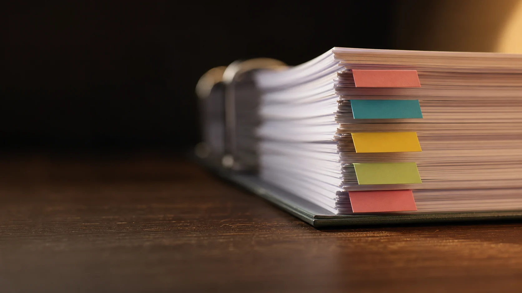 Close on the edge of a thick binder with coloured index tabs