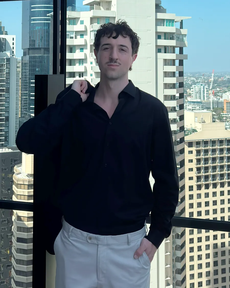 Kyle Hartwell on a rooftop with city towers behind him