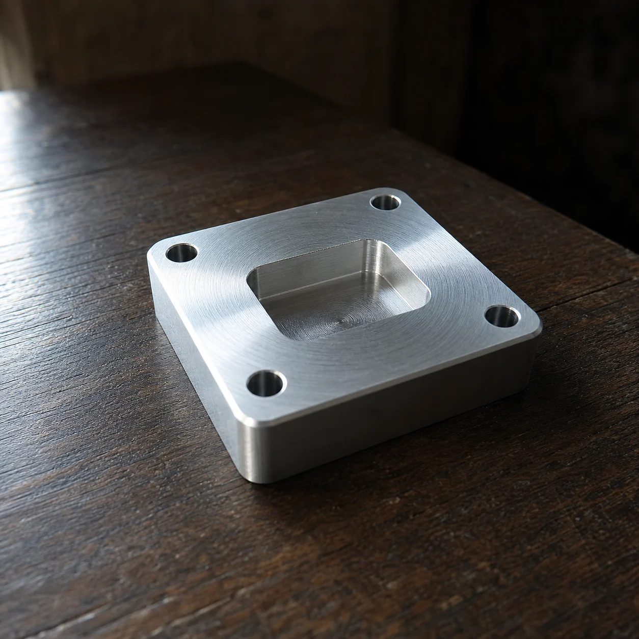 A machined aluminium block on a dark timber table
