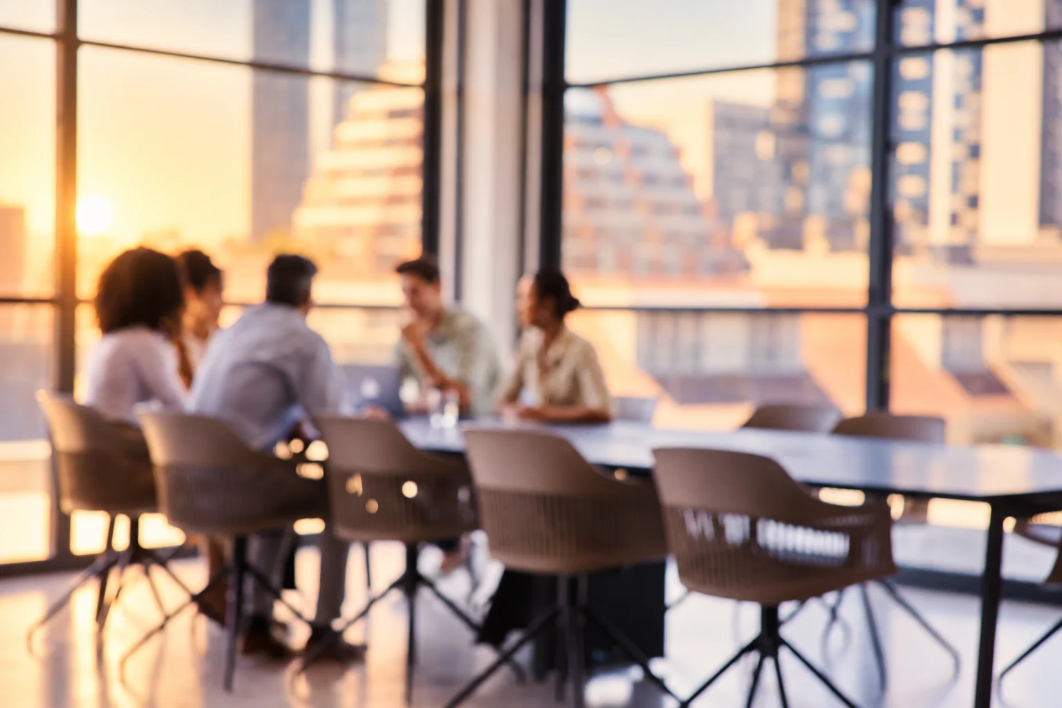 A small team around a meeting table at sunset, softly out of focus